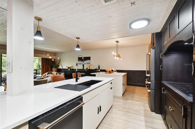 kitchen featuring decorative light fixtures, light hardwood / wood-style floors, white cabinetry, sink, and black appliances