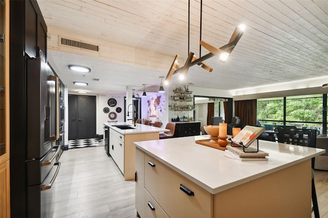 kitchen featuring wood ceiling, light hardwood / wood-style floors, sink, an island with sink, and a breakfast bar