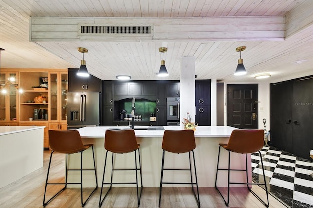 kitchen with a kitchen island with sink, wood-type flooring, a breakfast bar, wooden ceiling, and stainless steel built in refrigerator