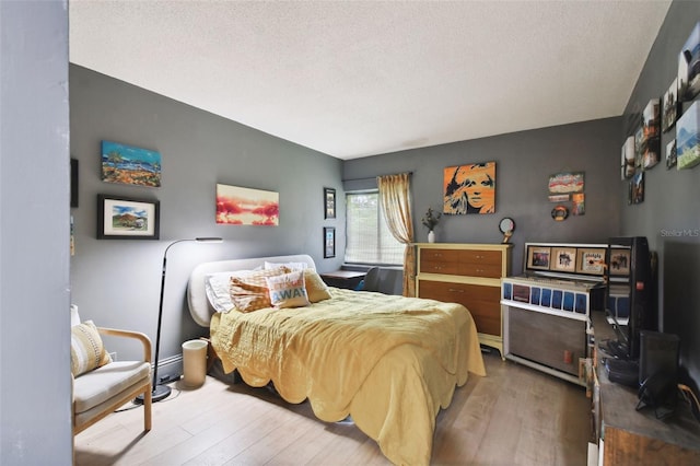 bedroom with a textured ceiling and wood-type flooring