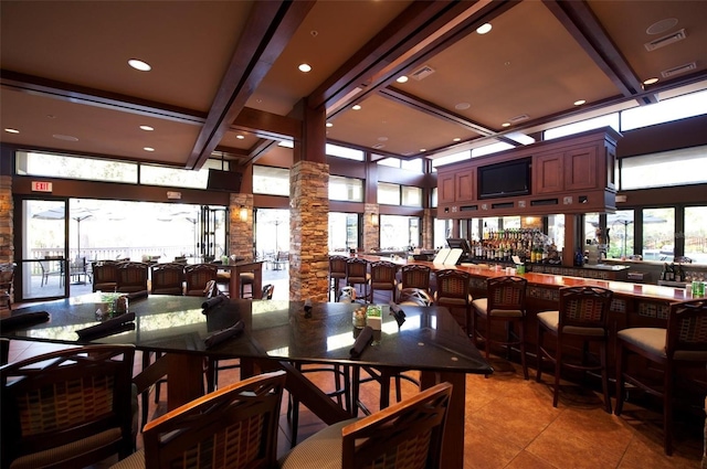 dining space featuring tile patterned flooring, indoor bar, beam ceiling, and ornate columns