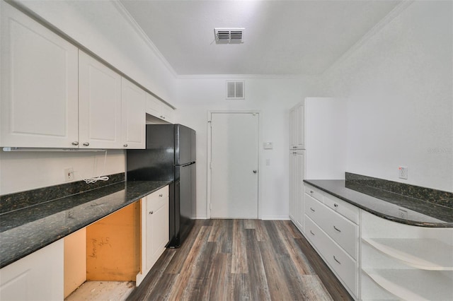 kitchen with ornamental molding, dark wood-type flooring, black refrigerator, and white cabinets