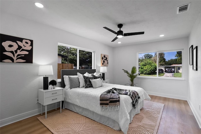 bedroom with multiple windows, ceiling fan, and wood-type flooring