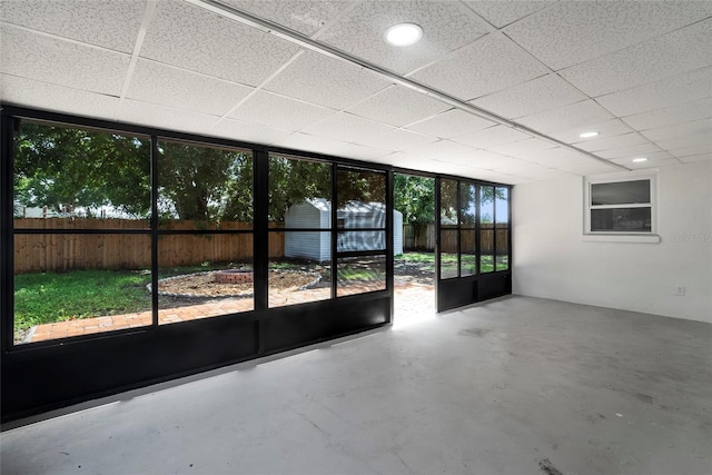 interior space with a healthy amount of sunlight, concrete flooring, and a drop ceiling