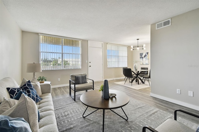 5095 Bay St NE Unit 306, Saint Petersburg, FL 33703 - living room with a notable chandelier, a textured ceiling, baseboards, visible vents, and wood finished floors