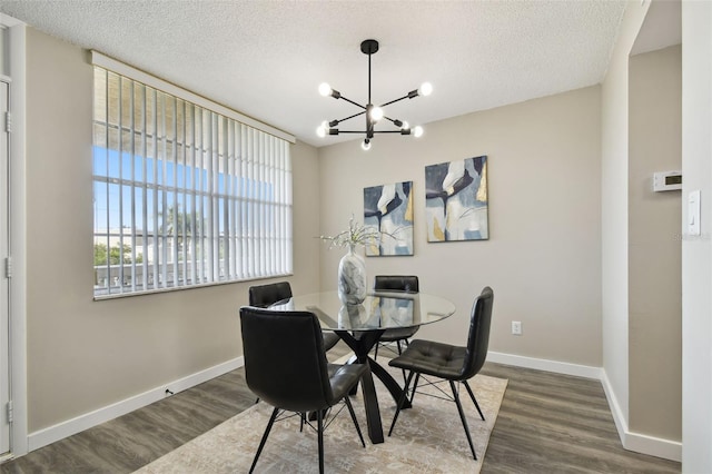 dining room with a textured ceiling, an inviting chandelier, and dark hardwood / wood-style flooring