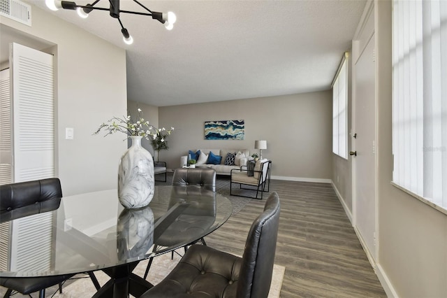 5095 Bay St NE Unit 306, Saint Petersburg, FL 33703 - dining space featuring wood finished floors, a notable chandelier, a textured ceiling, visible vents, and baseboards