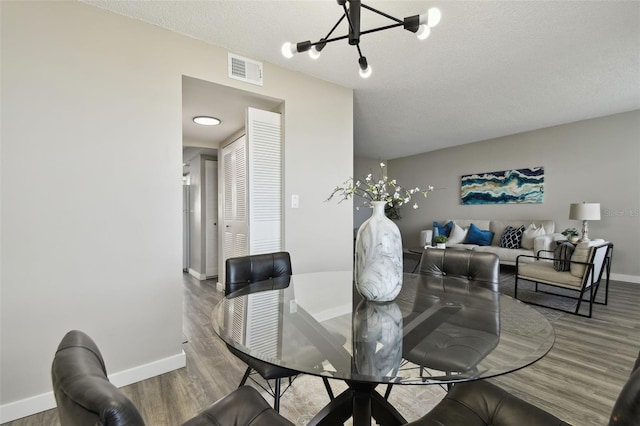 dining space featuring a textured ceiling, hardwood / wood-style floors, and a chandelier