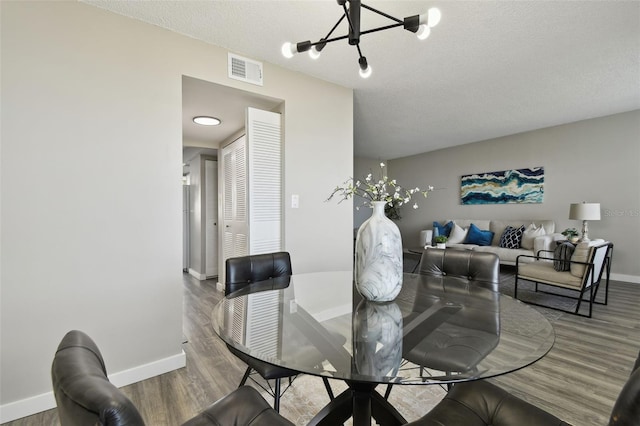 5095 Bay St NE Unit 306, Saint Petersburg, FL 33703 - dining space featuring a notable chandelier, baseboards, visible vents, and wood finished floors