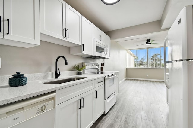 5095 Bay St NE Unit 306, Saint Petersburg, FL 33703 - kitchen featuring a sink, white appliances, light stone counters, white cabinetry, and baseboards