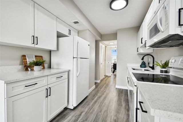 5095 Bay St NE Unit 306, Saint Petersburg, FL 33703 - kitchen with baseboards, white appliances, a sink, white cabinetry, and wood finished floors