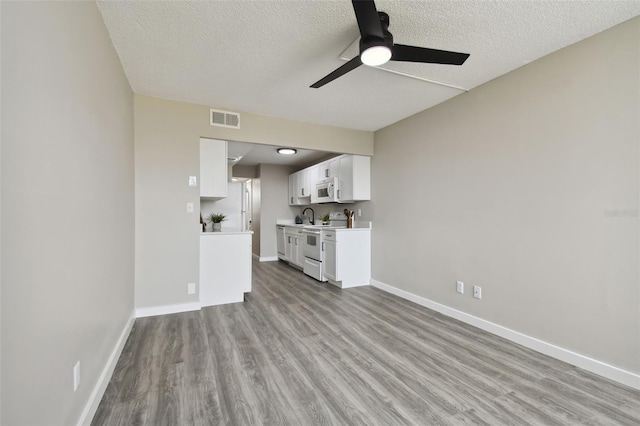 unfurnished living room featuring light wood-type flooring, a textured ceiling, and ceiling fan