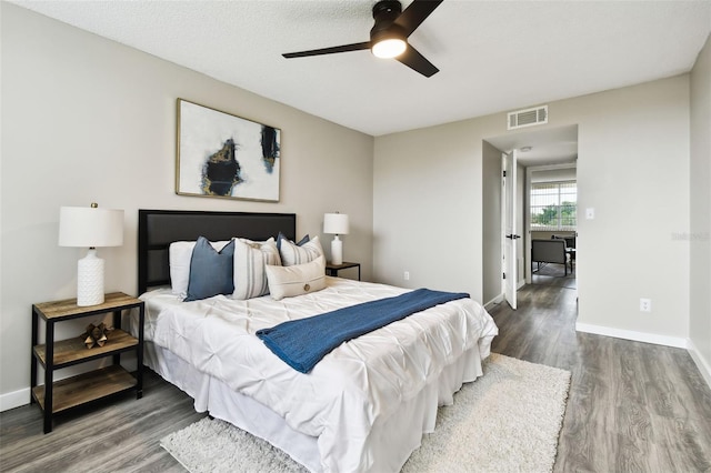 bedroom with hardwood / wood-style floors, ceiling fan, and a textured ceiling