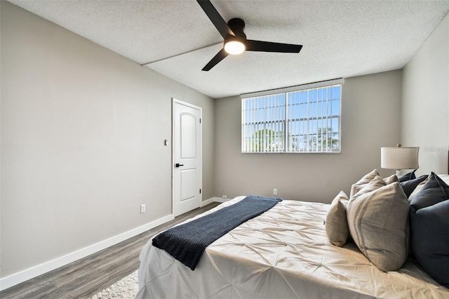 bedroom with ceiling fan, wood-type flooring, and a textured ceiling