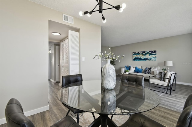 dining room featuring hardwood / wood-style floors, a notable chandelier, and a textured ceiling