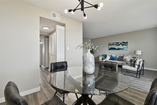 5095 Bay St NE Unit 306, Saint Petersburg, FL 33703 - dining area with wood finished floors, a textured ceiling, visible vents, an inviting chandelier, and baseboards
