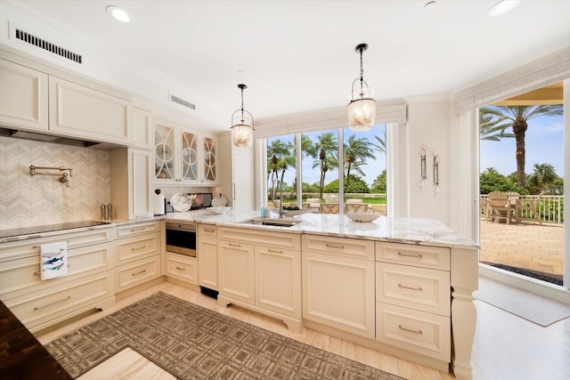 kitchen with decorative light fixtures, light stone counters, tasteful backsplash, and sink