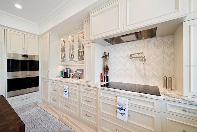 kitchen featuring crown molding, black electric stovetop, light stone countertops, and double oven