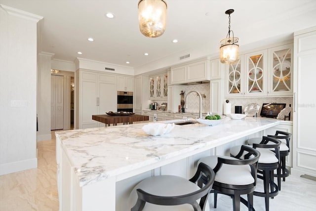 kitchen with hanging light fixtures, a kitchen bar, tasteful backsplash, and sink