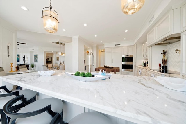 kitchen featuring decorative light fixtures, light stone countertops, double oven, black electric stovetop, and decorative backsplash