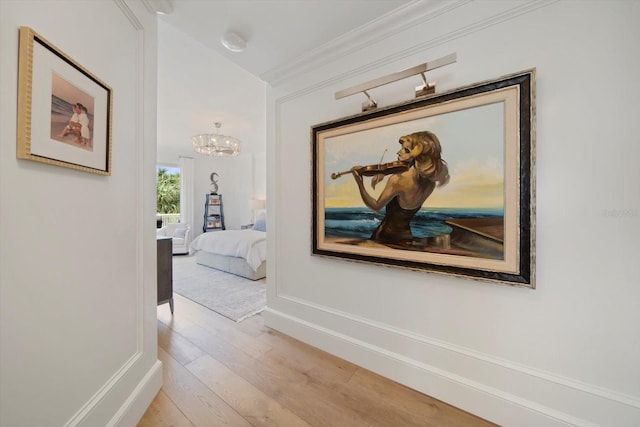 hallway featuring vaulted ceiling, an inviting chandelier, and light hardwood / wood-style floors