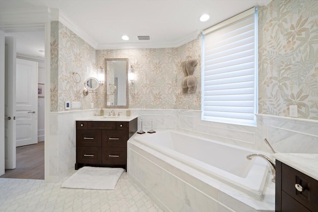 bathroom with ornamental molding, tiled bath, and vanity