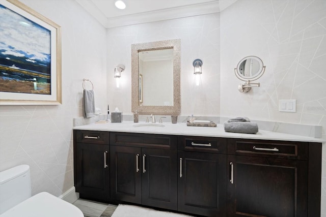 bathroom with vanity, toilet, ornamental molding, and tile walls