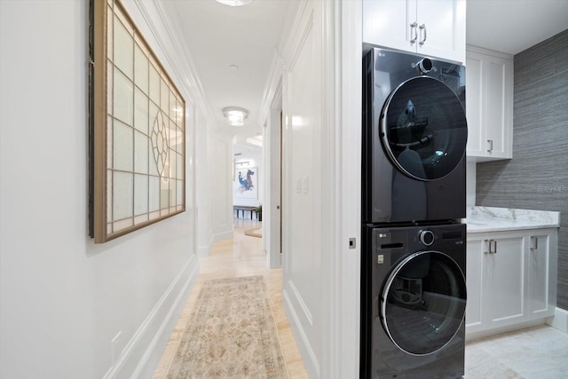 laundry area featuring cabinets and stacked washer / drying machine