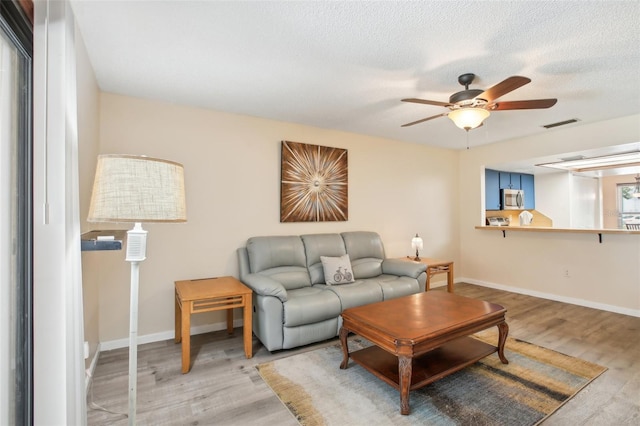 living room with a textured ceiling, hardwood / wood-style flooring, and ceiling fan