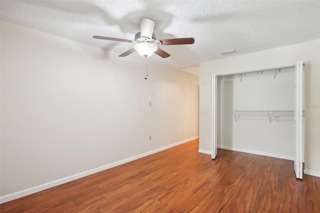 unfurnished bedroom featuring a closet, a textured ceiling, ceiling fan, and dark hardwood / wood-style floors