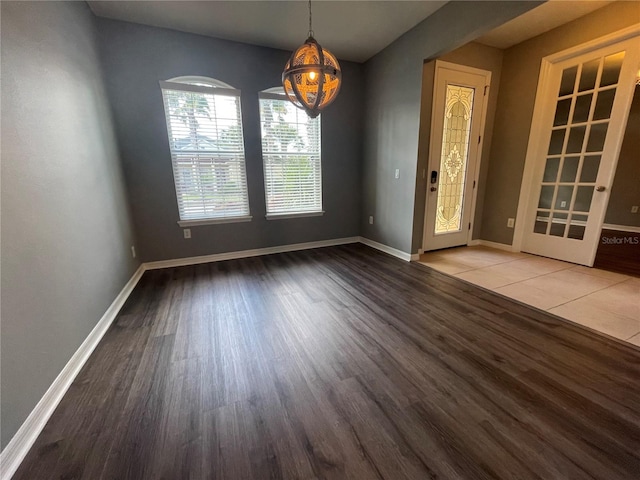 unfurnished dining area featuring a notable chandelier and hardwood / wood-style flooring