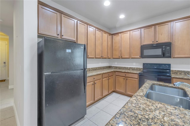 kitchen featuring black appliances, dark stone countertops, light tile patterned floors, and sink