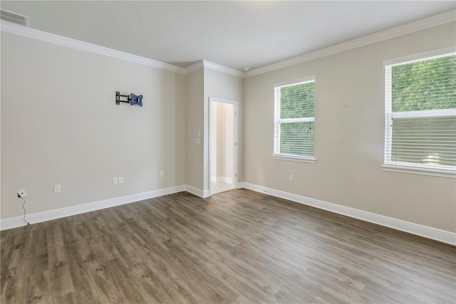 empty room with crown molding, a healthy amount of sunlight, and hardwood / wood-style flooring