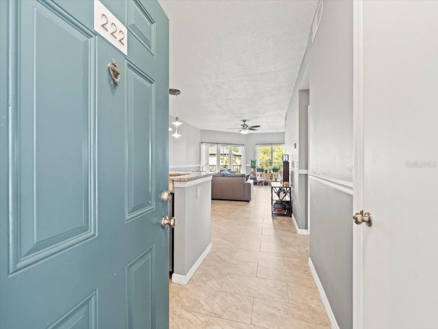 entryway featuring a textured ceiling, light tile patterned floors, and ceiling fan