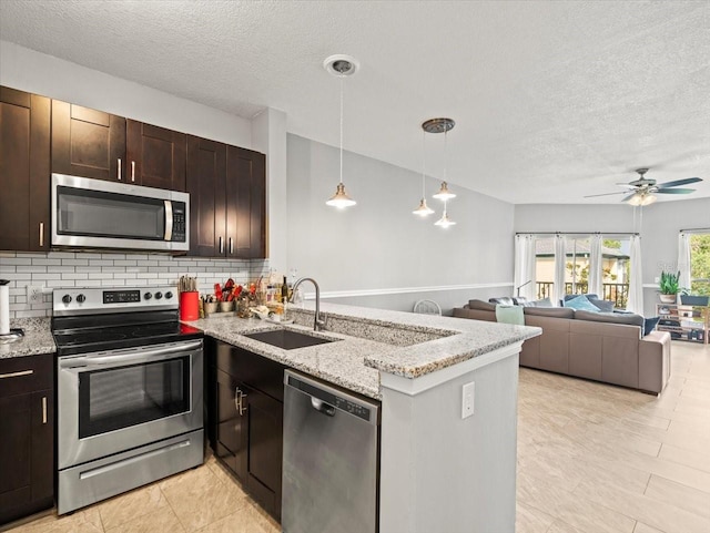 kitchen with appliances with stainless steel finishes, kitchen peninsula, sink, and ceiling fan