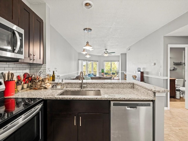 kitchen featuring appliances with stainless steel finishes, light stone counters, sink, ceiling fan, and tasteful backsplash