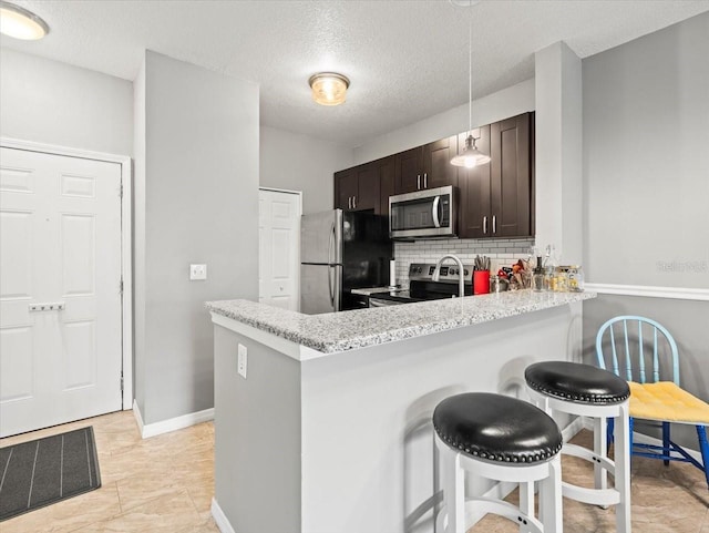 kitchen with a breakfast bar area, kitchen peninsula, stainless steel appliances, and decorative backsplash