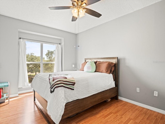 bedroom featuring ceiling fan, light hardwood / wood-style floors, and a textured ceiling