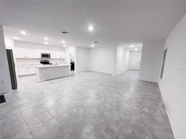 kitchen featuring visible vents, a kitchen island with sink, stainless steel appliances, white cabinetry, and open floor plan