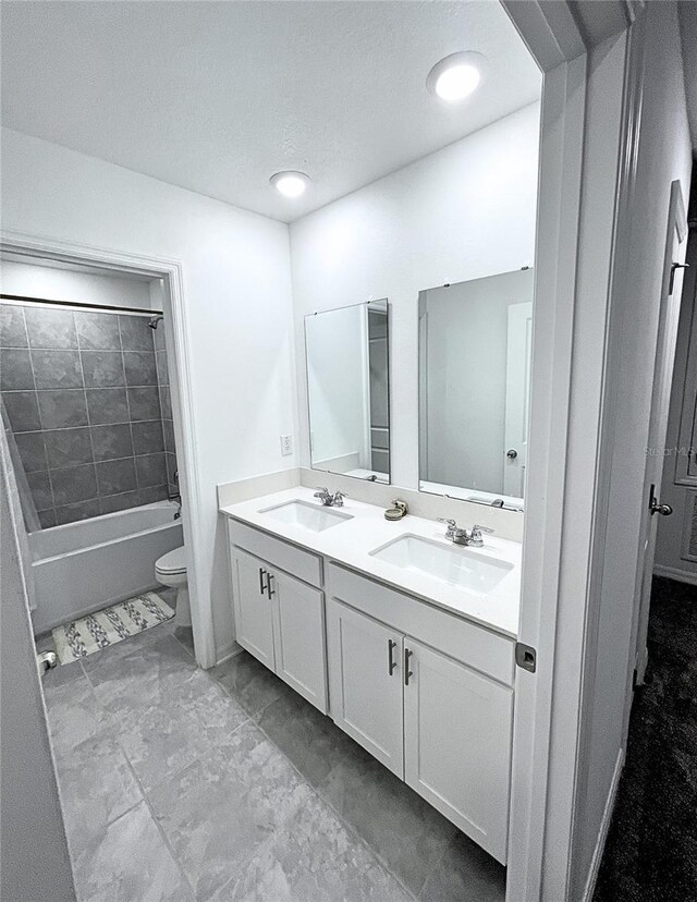 full bathroom featuring vanity, tiled shower / bath combo, and toilet