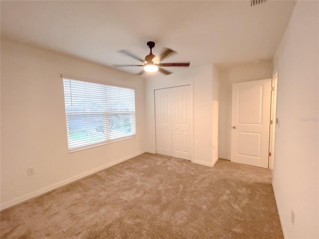 unfurnished bedroom with light carpet, a closet, and ceiling fan