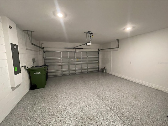 garage featuring concrete block wall, electric panel, a garage door opener, and recessed lighting