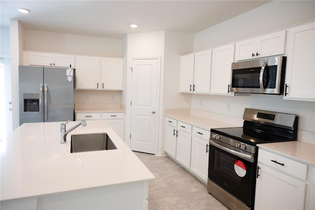 kitchen with white cabinetry, sink, stainless steel appliances, a center island with sink, and light tile patterned floors