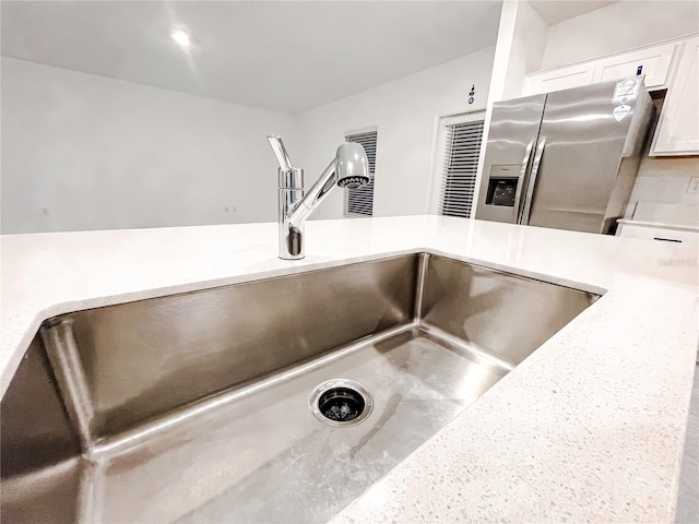 details with sink, white cabinets, and stainless steel refrigerator with ice dispenser