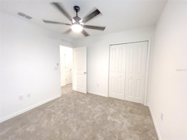 unfurnished bedroom featuring ceiling fan, light carpet, and a closet