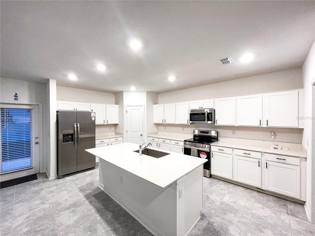 kitchen featuring visible vents, an island with sink, white cabinets, stainless steel appliances, and a sink