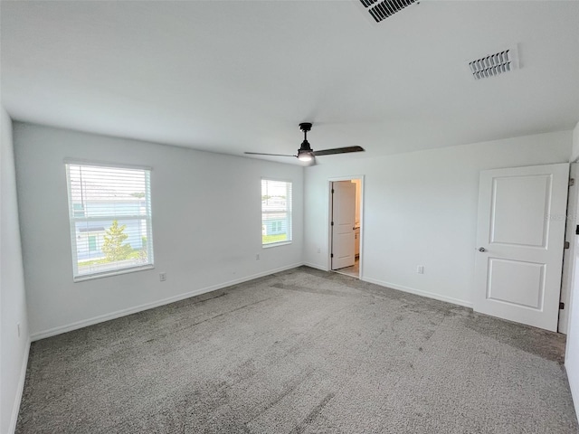 carpeted spare room with visible vents, baseboards, and ceiling fan