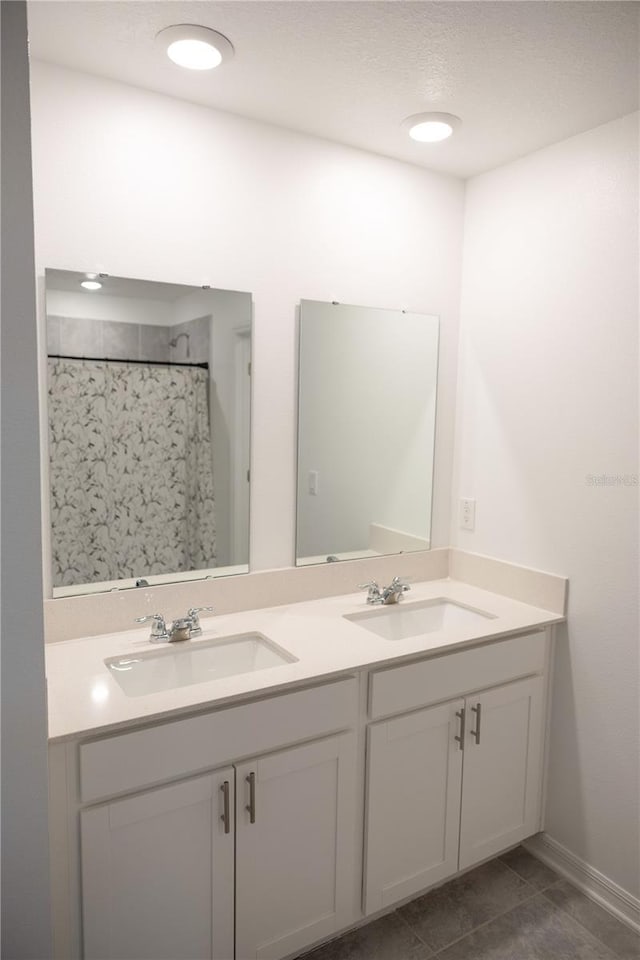 bathroom featuring double vanity, tile patterned flooring, curtained shower, and a sink