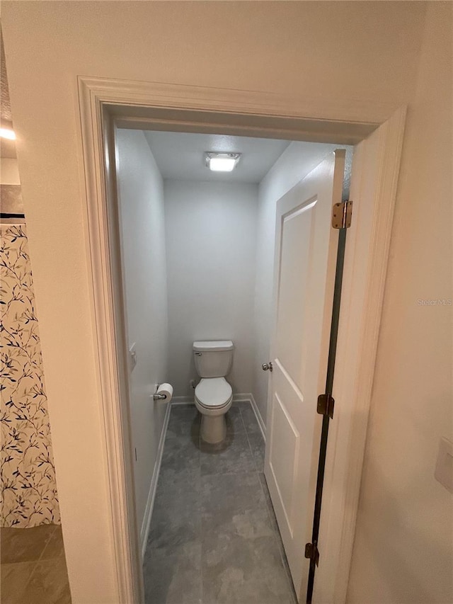 bathroom featuring tile patterned flooring, toilet, and baseboards