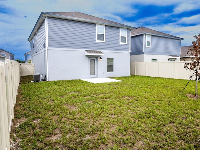 rear view of property featuring central air condition unit, a fenced backyard, a lawn, and stucco siding